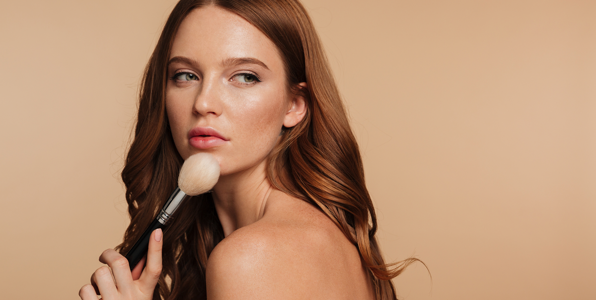 Woman with winged eyeliner applying makeup with a brush